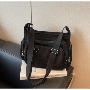 Detail of black corduroy tote bag with multiple zipper pockets and adjustable strap