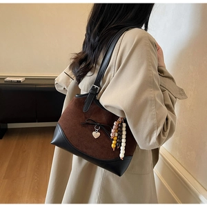 Detail of suede shoulder bag with heart pendant, bow and bohemian beaded tassel charms