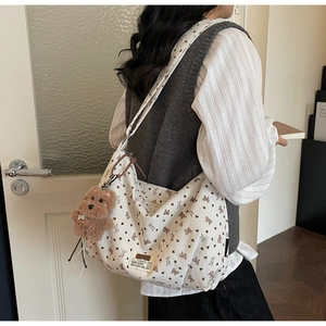 Détail d'un sac en toile avec motifs cœurs et un pendentif ours en peluche marron
