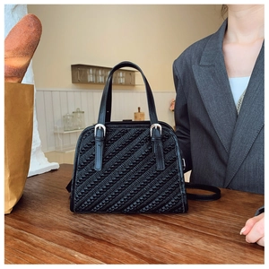 Vista detallada de la textura de cuero plisado negro y la hebilla plateada de este bolso