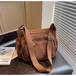 Detail of brown corduroy tote bag featuring multiple functional zippers and metal hardware
