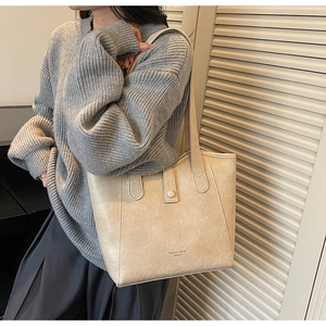Close-up of beige tote bag with litchi texture and elegant metal button detail