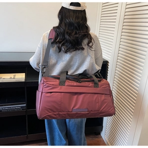 Detail of burgundy sports duffel bag with reinforced handles and adjustable strap