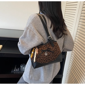 Close-up of leopard print shoulder bag with bow, heart pendant and beaded charms