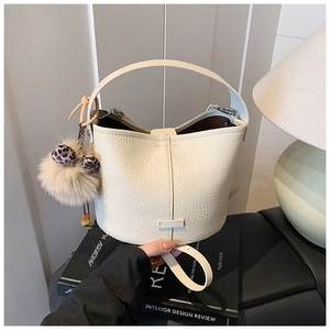 Detail of cream bucket bag with lychee texture leather and leopard pompom charm