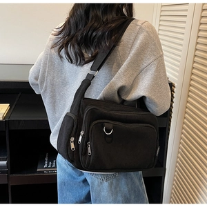 Detailed view of the black corduroy tote bag with side pockets on a person