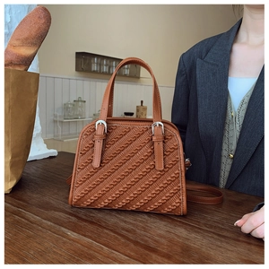 Detalle de bolso de cuero plisado color caramelo con hebilla sobre mesa madera