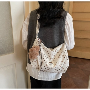 Sac fourre-tout en velours beige à pois avec nœuds et pendentif ours porté par un modèle