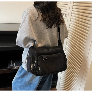 Detail view of black corduroy crossbody tote bag featuring multiple zipper pockets and D-ring