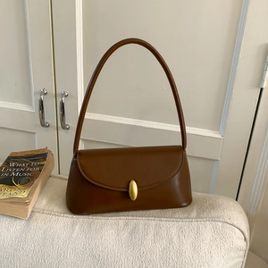 Detail view of a vintage brown leather underarm bag with a golden oval metal buckle closure