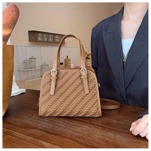 Detalle del bolso cuadrado marrón con textura de sarga y herrajes metálicos plateados