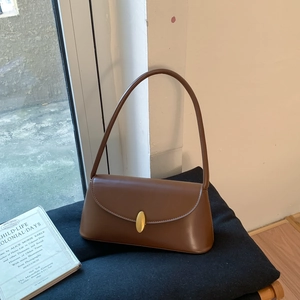 Detail of matte brown leather shoulder bag featuring elegant golden oval metal clasp