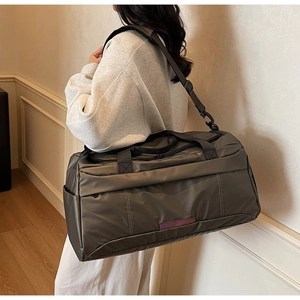 Detail view of large olive travel duffel bag with shoulder strap and reflective strip