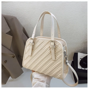 Vista detallada del bolso crema con textura plisada ondulada y herrajes metálicos plateados