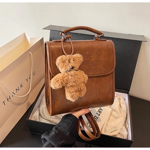 Dettaglio dello zaino vintage in pelle PU marrone con testo goffrato e orsetto peluche