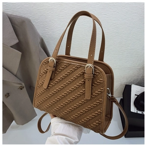 Detalle de un bolso bandolera marrón plisado con asas ajustables y textura ondulada