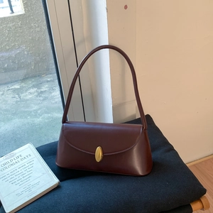 Detail of dark chocolate vintage underarm bag featuring a gold oval metal twist lock