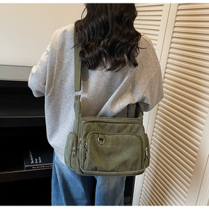 Detail showing dark green corduroy tote bag with multiple pockets and metal zipper rings