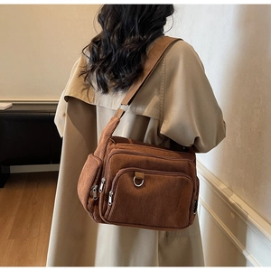 Detail showing the brown corduroy texture and multiple functional zipper pockets on the bag