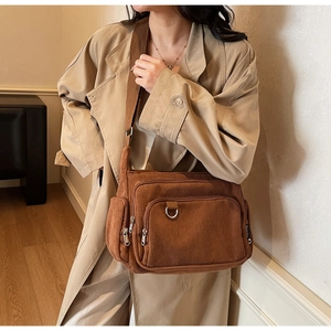 Detail of brown corduroy tote bag with multiple zip pockets and wide woven shoulder strap