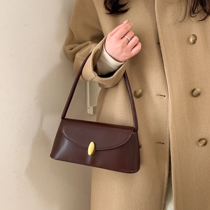 Detail of vintage dark brown leather underarm bag with gold oval buckle on wool coat