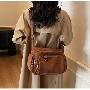Detailed view of brown corduroy crossbody bag with multiple zip pockets and wide strap