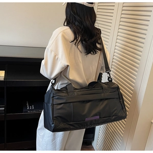 Detail of black waterproof gym bag showing shoulder strap and large side pockets