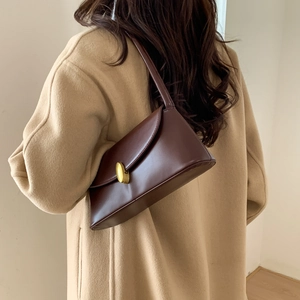 Detail view of a vintage dark brown leather underarm bag with gold oval buckle and fine stitching