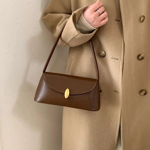 Detail of vintage brown leather underarm bag with gold oval clasp on wool coat