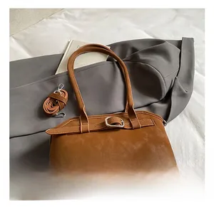 Détail du sac en cuir marron avec boucle métallique et bandoulière amovible réglable