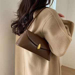 Detail showing the brown leather shoulder bag worn with an elegant cashmere coat