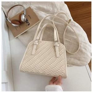 Detalle de bolso bandolera blanco crema con textura de pliegues ondulados y hebillas de plata