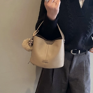 Detail of beige lychee pattern bucket bag with chic leopard print pompom charm accessory