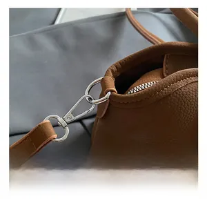 Détail du fermoir en métal argenté et bandoulière en cuir à motif litchi du sac