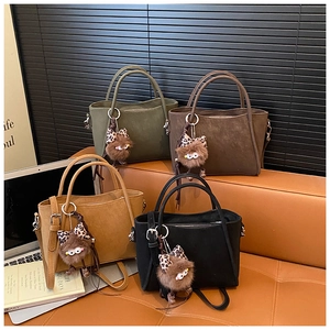 Detail of four matte vintage bucket bags in black, brown, green, and yellow with plush charms