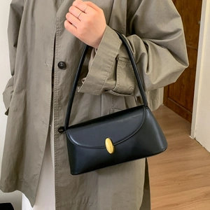 Detail of vintage black leather baguette bag featuring a gold oval hardware turn-lock