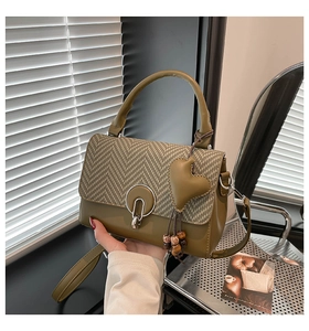 Detalle de bolso bandolera vintage verde oliva con solapa de pata de gallo y dije corazón