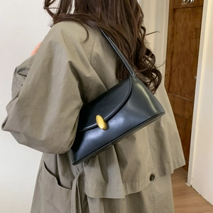 Retro black leather shoulder bag with gold oval buckle shown on a grey winter coat