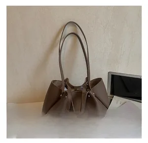Detail of dark brown leather tote bag showing unique pleated structure and metal buckle