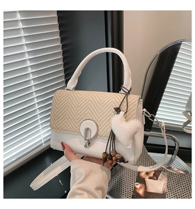 Detalle de textura tejida beige y bolso de cuero blanco con colgante de corazón