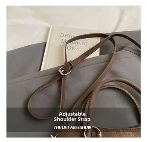 Detail of adjustable leather strap with silver metal buckle on a brown bucket bag