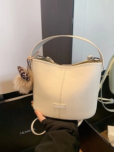 Elegant cream white pebble leather bucket bag with leopard print pompom charm and top handle