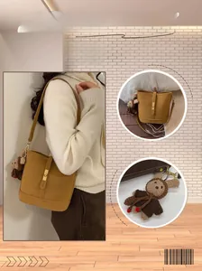 Detail view of a camel leather bucket bag featuring a gold clasp and cute rabbit charm