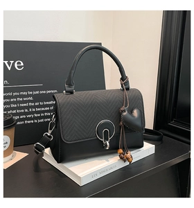 Detalle de bolso bandolera negro con cierre de anillo plateado y colgante de corazón con cuentas
