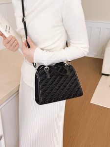 Bolso trapezoidal negro minimalista con cuero texturizado diagonal y detalles plateados