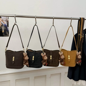 Detail view of four matte leather bucket bags in various colors with cute bear pendants