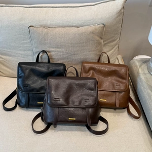 Detailed view of three vintage leather backpacks in black, dark coffee and brown on a sofa