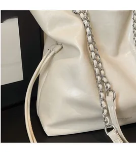Detail of white faux leather tote with textured finish and silver metal chain strap