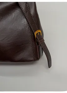 Dettaglio della borsa in pelle marrone scuro con fibbia dorata e cuciture pulite