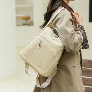 Detail view of cream woven leather backpack with rabbit logo and wide fabric strap
